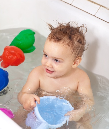 Toddler swimming with toys in bathの写真素材