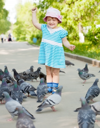 two-year girl with doves  in the city streetの写真素材