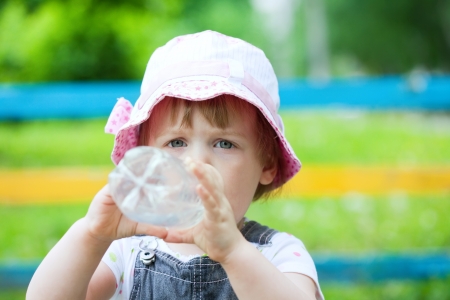  2 years baby drinks from plastic bottle in parkの写真素材