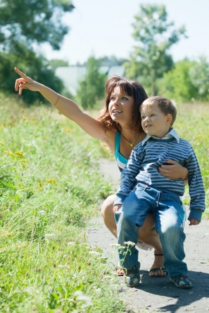 Happy mother with boy poiting away in parkの写真素材