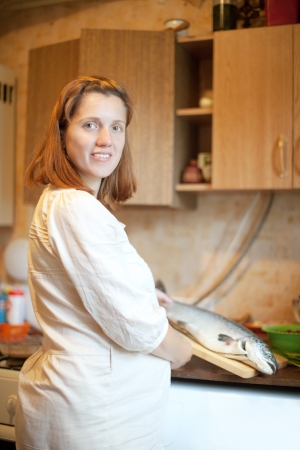 pregnant woman with salmon in the kitchen の写真素材