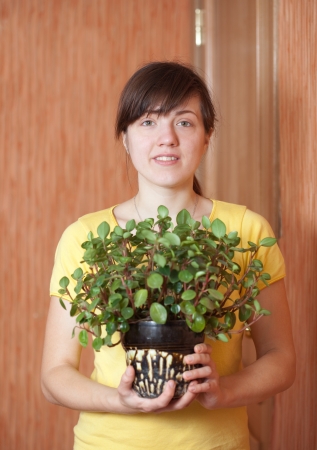 Young woman with  Peperomia obtusifolia  in flowering pot  at her homeの写真素材