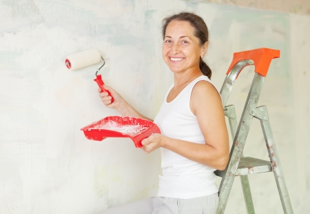 Happy mature woman makes repairs at homeの写真素材