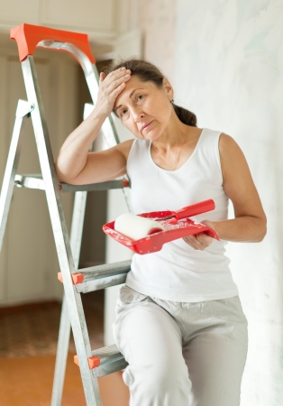 weariness mature woman makes repairs at homeの写真素材