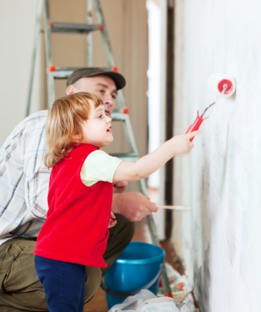 child  with father paints wall  at homeの写真素材