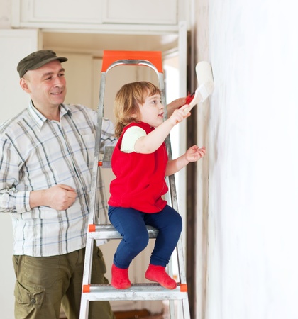 father with child paints wall  at homeの写真素材