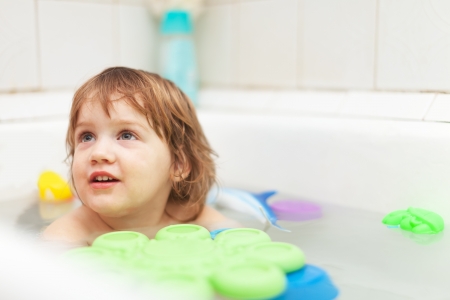 two-year baby girl bathes with toys in bathの写真素材