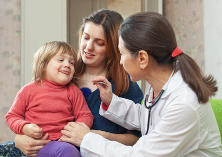  mature pediatrician doctor examining 2 years child in home 