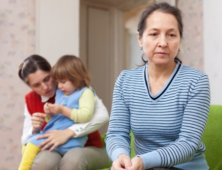 Conflict between generations. Sad mature grandmother against daughter with babyの写真素材