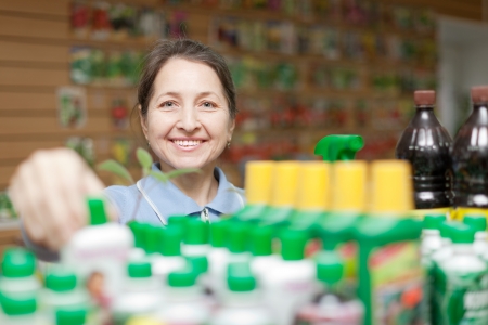  female mature gardener chooses fertilizer in bottle at store の写真素材