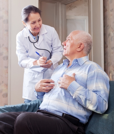 Senior man tells the mature doctor the symptoms of malaise on couch.の写真素材