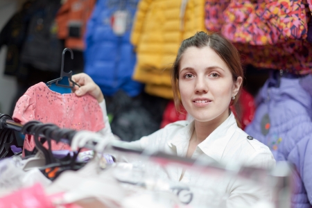 woman  chooses  dress for daughter at  children's clothes storeの写真素材