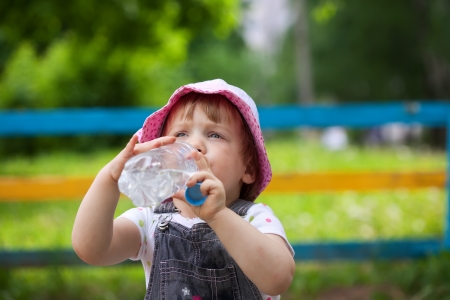 2 years child drinks from plastic bottle in parkの写真素材