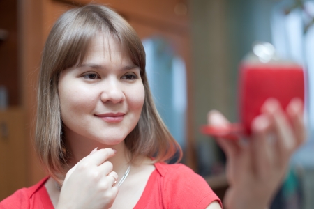 young woman stares on  face in mirror at homeの写真素材