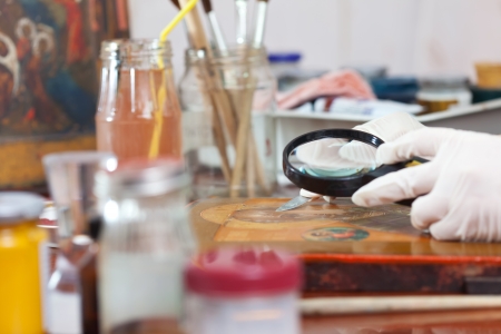 accurate restoration of old Christian icon with magnifying at workshopの写真素材