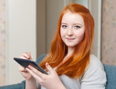 Young girl uses e-book  or tablet computer  in home interiorの写真素材