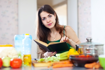 young  woman reads cookbook for recipe at kitchenの写真素材