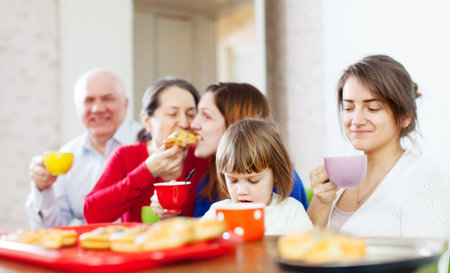 family having tea with cakes at home together