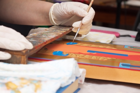 Closeup of artist hands painting of new icon with brush at workshopの写真素材