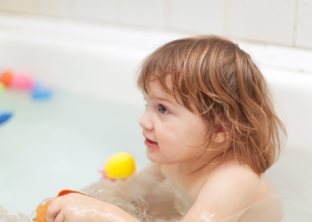  baby girl bathes with toys in bathの写真素材