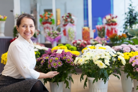 Happy mature woman with chrysanthemum at flower storeの写真素材