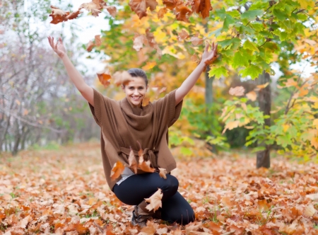 Woman throws autumn leaves in the parkの写真素材