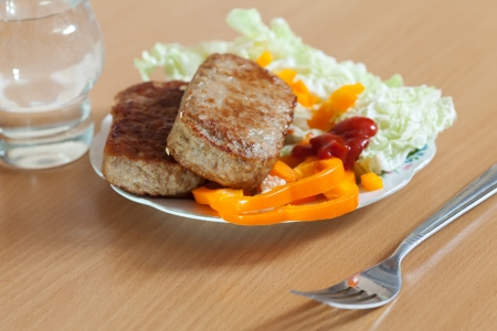 Fast food. Two fried cutlets with lettuce on white plate at tableの写真素材