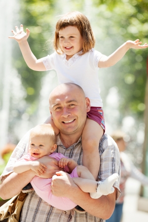 Outdoor portrait of happy father with two adorable daughtersの写真素材