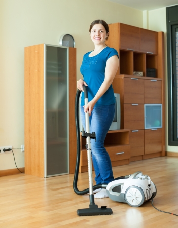 full length shot of woman cleans with vacuum cleaner at homeの写真素材