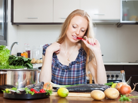 pensive housewife is thinking how to cook seabass fish at kitchenの写真素材