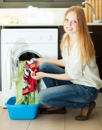 Long-haired woman doing laundry at her homeの写真素材