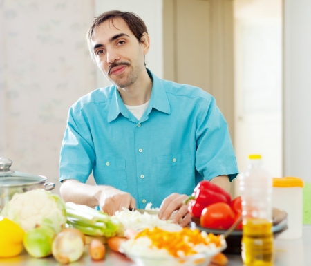 man with vegetables on cutting board in domestic kitchen at homeの写真素材