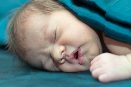 newborn baby girl sleeps under blanketの写真素材