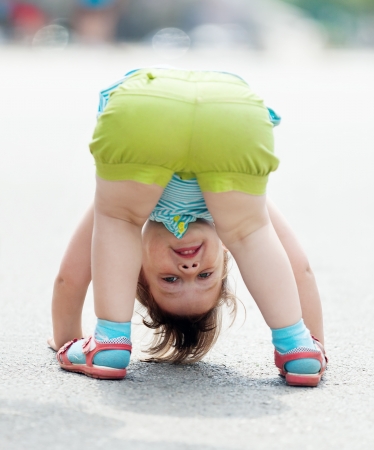 three-year baby girl playing upside down in streetの写真素材