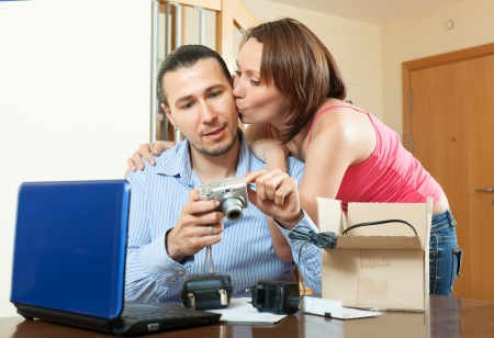 Happy couple  unpacking new digital camera  in home interiorの写真素材