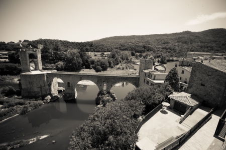 Vintage photo of medieval bridge over river in Besalu. Catalonia. Imitation of old imageのeditorial素材