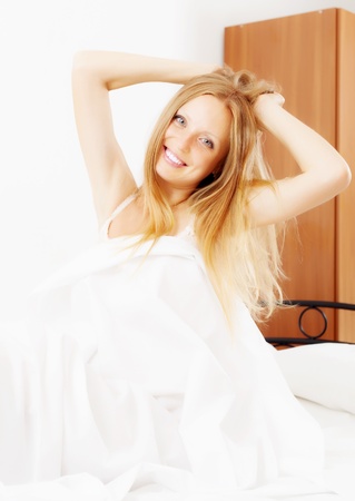 Long-haired woman waking in  bed at homeの写真素材
