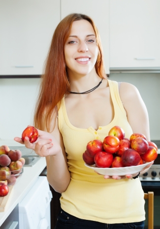 Smiling girl with nectarines at home kitchenの写真素材