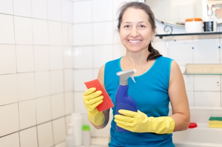mature woman cleans bathroom with sponge at her homeの写真素材