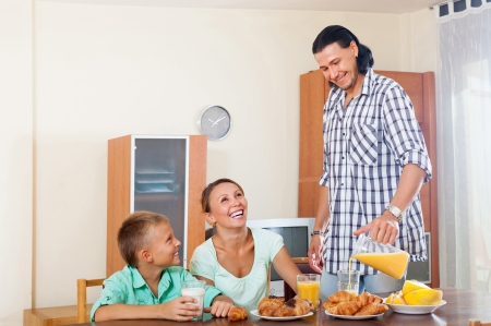 Happy man and woman with boy having breakfast at home in morningの写真素材