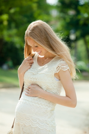 Smiling pregnant woman walks in summer parkの写真素材