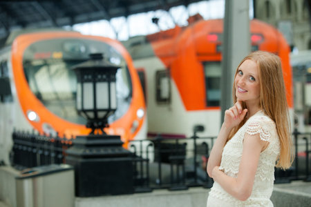 Long-haired pregnant woman waiting train at railway station