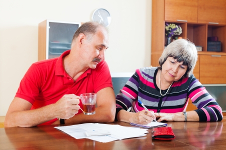 mature couple fills in questionnaire together at homeの写真素材