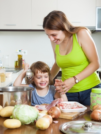 Smiling woman with little girl cooking together at home kitchenの写真素材
