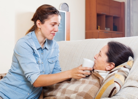  Adult woman caring for sick mature mother in living roomの写真素材