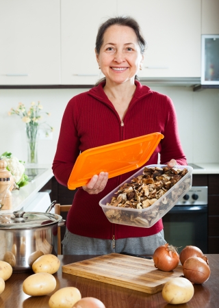 mature housewife with dried mushrooms in home kitchenの写真素材