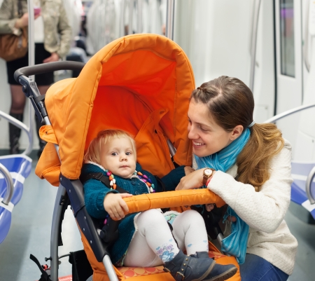 Smiling woman with child in stroller at subwayの写真素材