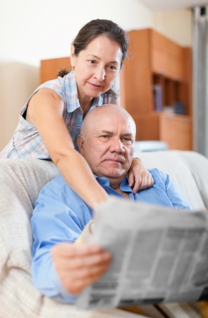 Portrait of a smiling happy grandparents at home with newspaperの写真素材