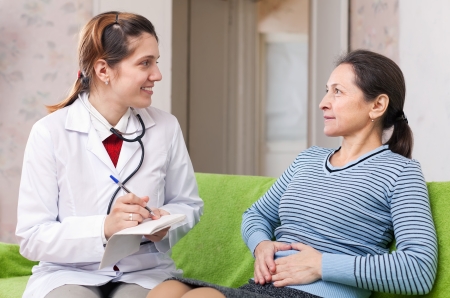 Mature woman complaining  to doctor about stomachache at  hospitalの写真素材