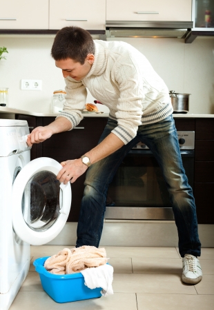  Handsome man loading clothes into the washing machine  in homeの写真素材